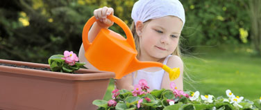 child using a watering can with water collected from a garden water butt